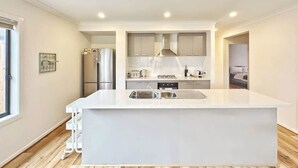 Une cuisine moderne dotée d’un îlot central, d’appareils électroménagers en acier inoxydable et offrant une vue sur la chambre adjacente.