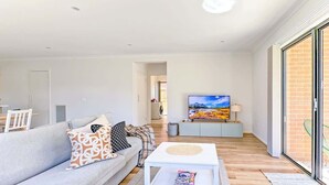 Un salon moderne avec un canapé, une table basse et un téléviseur à écran plat.