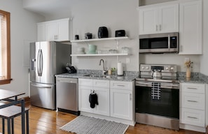 A modern kitchen with white cabinetry, stainless steel appliances, and a granite countertop.