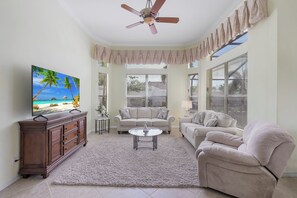 Ein Wohnzimmer mit Fernseher, zwei Sofas, einem Couchtisch und einem Deckenventilator.