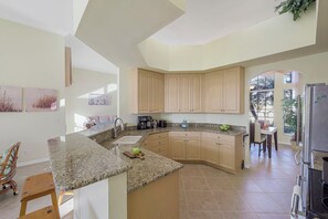 Eine moderne Küche mit Granit Arbeitsplatten, beigefarbenen Schränken und einem Essbereich mit Tisch und Stühlen.