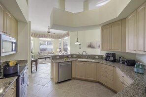 Enjoy cooking in this well-equipped kitchen with a central island, appliances, and a large sink.