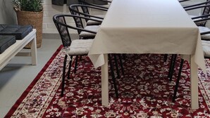 A conference room with a white table, black chairs, a red floral carpet, a white brick wall, a window with a view of trees, and a ceiling light. - THE Roomz  (Kotka)