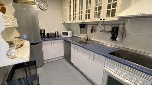 Eine moderne Küche mit weißen Schränken, einem Edelstahlkühlschrank, einer Mikrowelle, einer Spüle und einem Backofen.