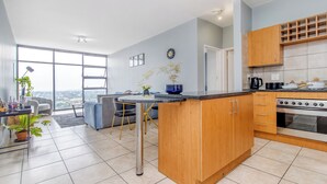 Een moderne keuken met houten kastjes, een inbouwoven en een eethoek met een tafel en stoelen.