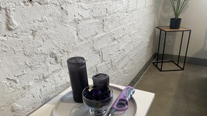 A table with a plate holding a glass of water, a black candle, and a purple candle holder.