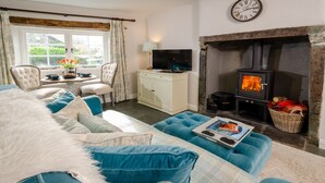 A cozy living room with a sofa, a television, a fireplace, and a dining area with a table and chairs. - Bank View - One Bedroom House, Sleeps 2 (Chapel Stile)
