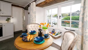 A dining area with a wooden table, chairs, and a view of the garden through a window. - Bank View - One Bedroom House, Sleeps 2 (Chapel Stile)