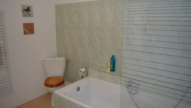 Casa de banho com sanita, banheira e cabine de duche em vidro.