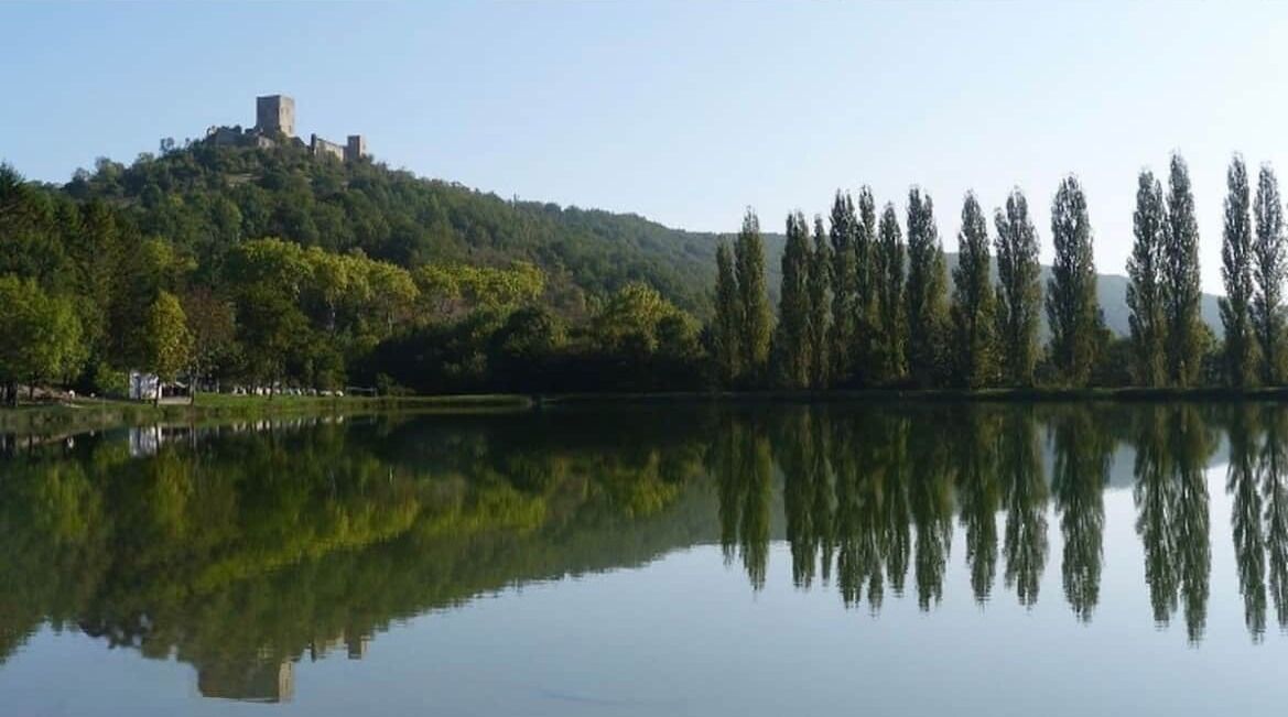 Un castillo en una colina con un lago tranquilo al frente.