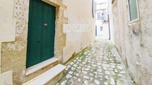 A narrow alleyway with a green door and steps leading to a building. - Historic home with a sea-view terrace in the heart of Otranto - Marea Stays Collection (Otranto)