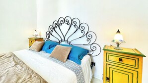 A neatly made bed with a decorative metal headboard, a bedside table with a lamp, and a small cabinet. - Historic home with a sea-view terrace in the heart of Otranto - Marea Stays Collection (Otranto)