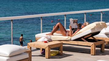 Relax in comfort with a sea view from our outdoor lounge area, featuring loungers and a table.