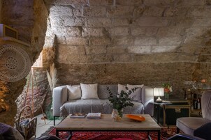 Uma sala de estar acolhedora com uma parede de pedra, um sofá, uma mesa de centro e uma mesa lateral com um abajur e um vaso.