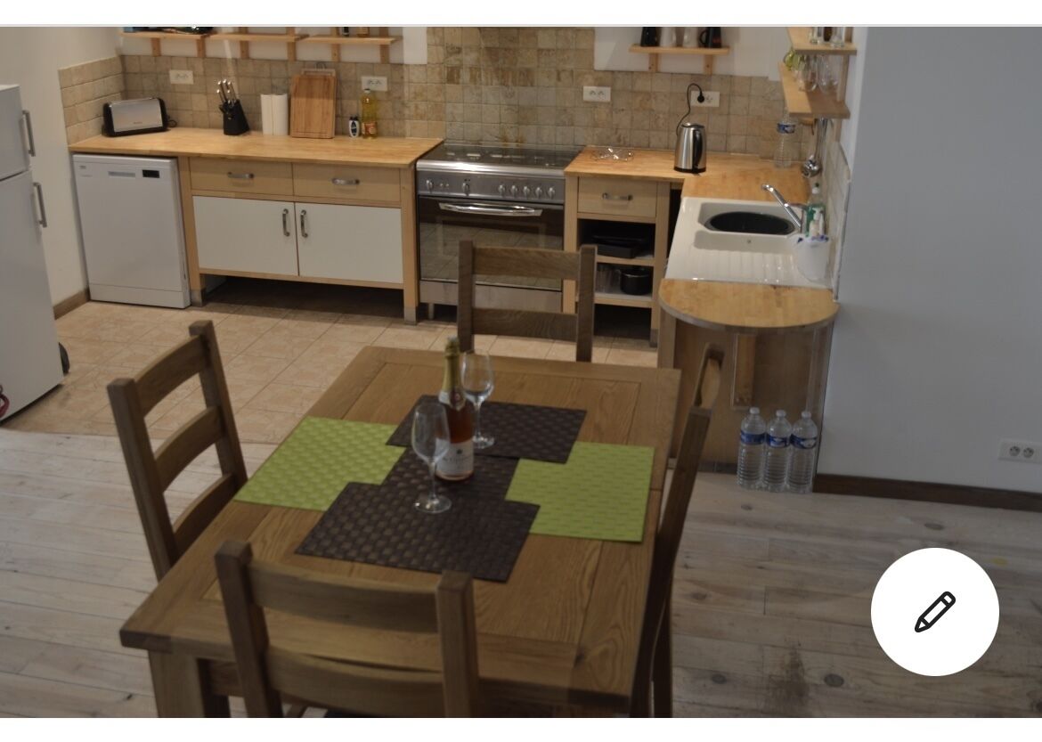 A compact kitchen with a dining area, including a table with chairs, a small refrigerator, a stove, and a sink.