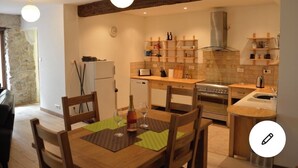 A compact kitchen with a dining area, featuring a built-in oven, a stove, and a sink. - Lovely renovated Cottage in Puivert (Puivert)