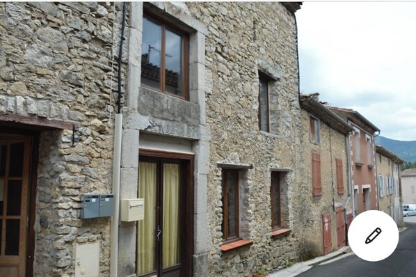 Un edificio de piedra con múltiples ventanas y puertas, que presenta un estilo arquitectónico tradicional.