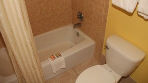 A bathroom with a bathtub, toilet, and a shower curtain. - Cruise Port Inn (Cocoa)
