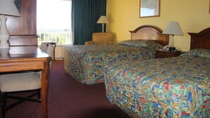 A hotel room with two beds, a desk, a chair, and a window with curtains. - Cruise Port Inn (Cocoa)
