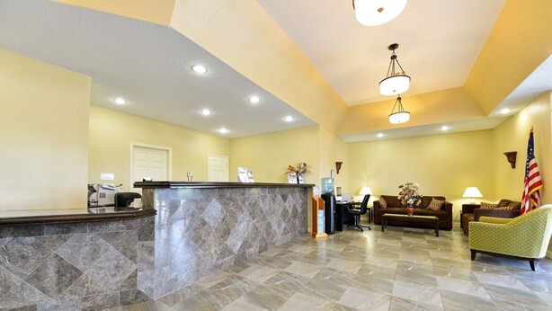 A lobby with a reception desk, seating area, and a flag. - Cruise Port Inn (Cocoa)