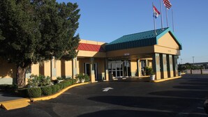 A hotel with a red roof, two American flags, and a parking lot with a yellow curb. - Cruise Port Inn (Cocoa)