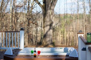 A hot tub on a wooden deck with a white fence and trees in the background. - Beer/Wineries, firpit & hottub (Crozet)