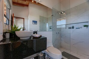 A modern bathroom with a large sink, toilet, and glass shower enclosure.