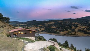 Une maison avec un toit rouge, un chemin de pierres et un lac en arrière-plan.