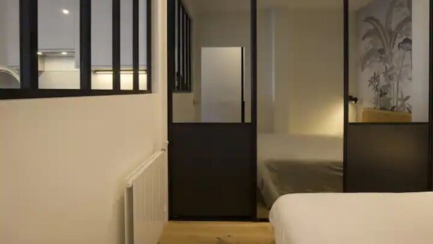 Een moderne hotelkamer met een bed, een nachtkastje en een groot raam.