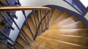 Una escalera en espiral de madera con barandilla y balaustradas de metal.