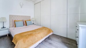 Un dormitorio con una cama grande, dos mesitas de noche, un armario blanco y una decoración de cabeza de ciervo en la pared.