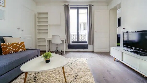 Una sala de estar moderna con sofá, una mesa de centro, televisor y balcón con vistas.
