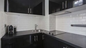 Una cocina moderna con gabinetes negros, un lavamanos de acero inoxidable y una encimera negra.