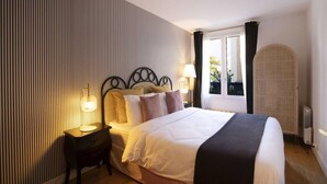 A hotel room with a bed, bedside tables, a lamp, a window with curtains, and a radiator. - Havre de paix avec balcon (Paris)