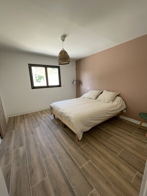 Une chambre à coucher avec un lit, une fenêtre et un luminaire suspendu.