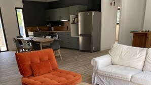 Ett modernt vardagsrum med ett soffbord i trä, en vit soffa och en orange fåtölj.