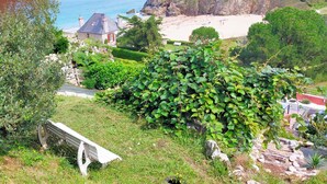 Eine Küstenlandschaft mit einem Steinhaus, einer Bank und einem gepflegten Garten.