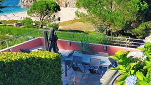 Eine Terrasse mit Sitzgelegenheiten, Blick auf den Strand und eine felsige Küstenlinie.