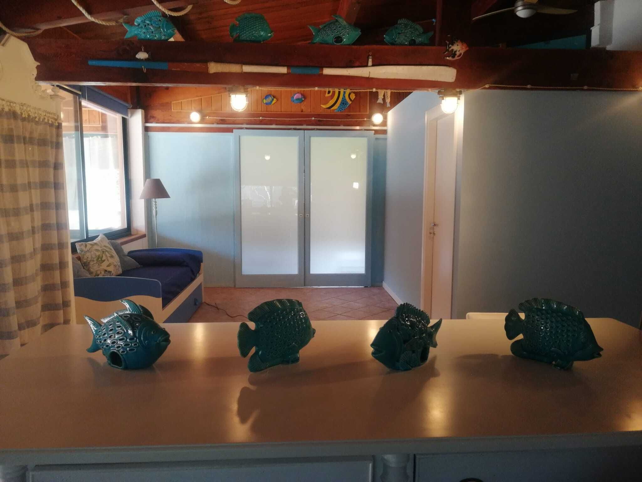 Une pièce avec un plafond en bois, un canapé, une table décorée de poissons et une porte coulissante dotée de panneaux en verre dépoli.