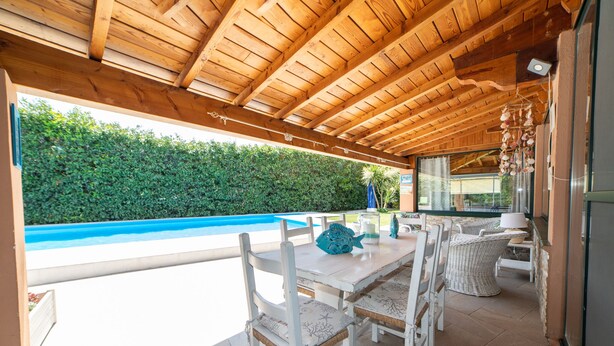 An outdoor patio with a wooden ceiling, white wicker furniture, and a view of a swimming pool. - BEAUTIFUL APARTMENT X 5 WITH HOT-HUB POOL ABOUT 2 KM FROM THE SEA (Imperia)
