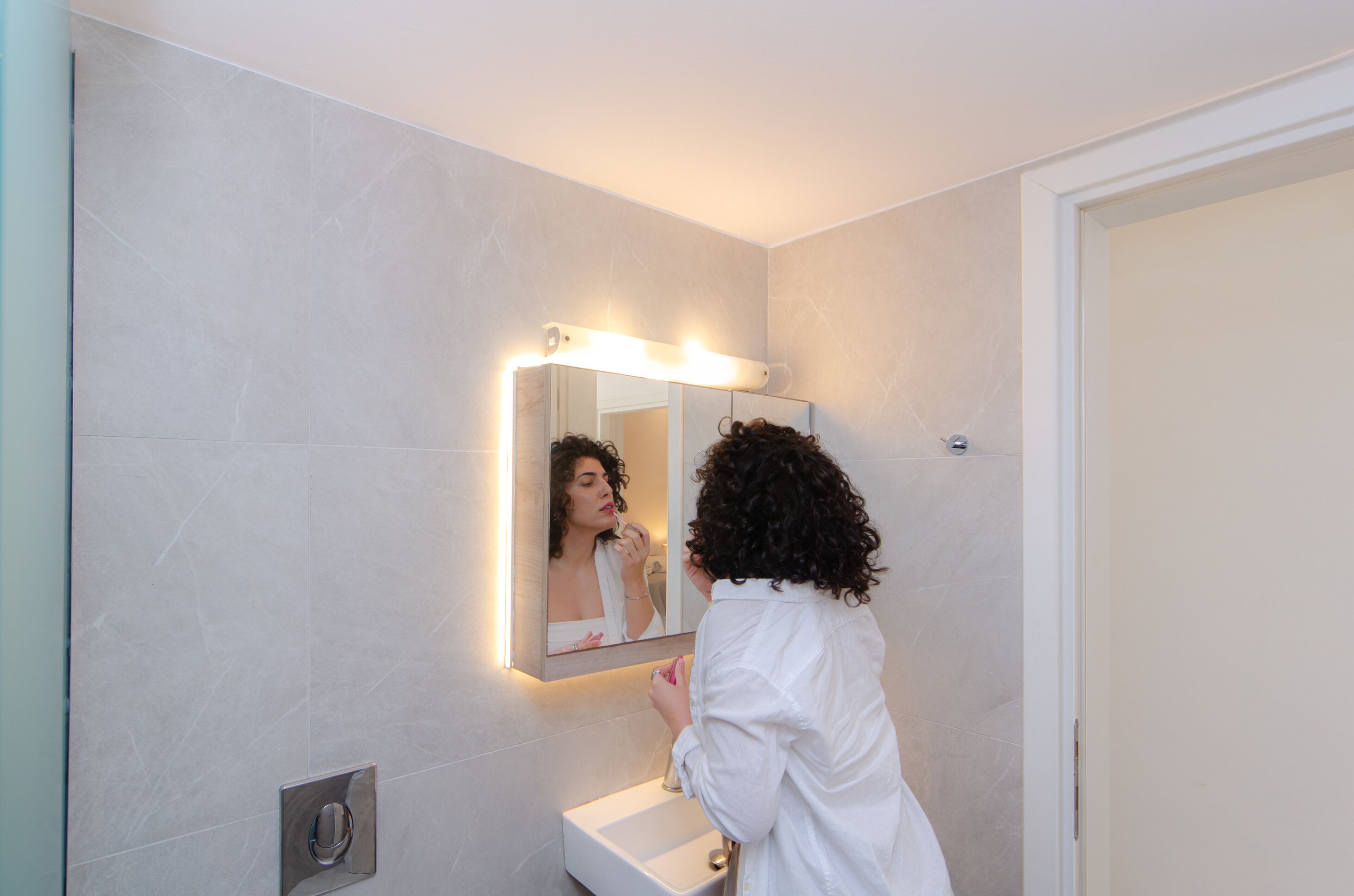 A bathroom with a mirror, light fixture, and a sink.