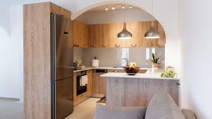 Eine moderne Küche mit Holzschränken, einem Edelstahlkühlschrank und einer zentralen Kochinsel mit Obstschale.