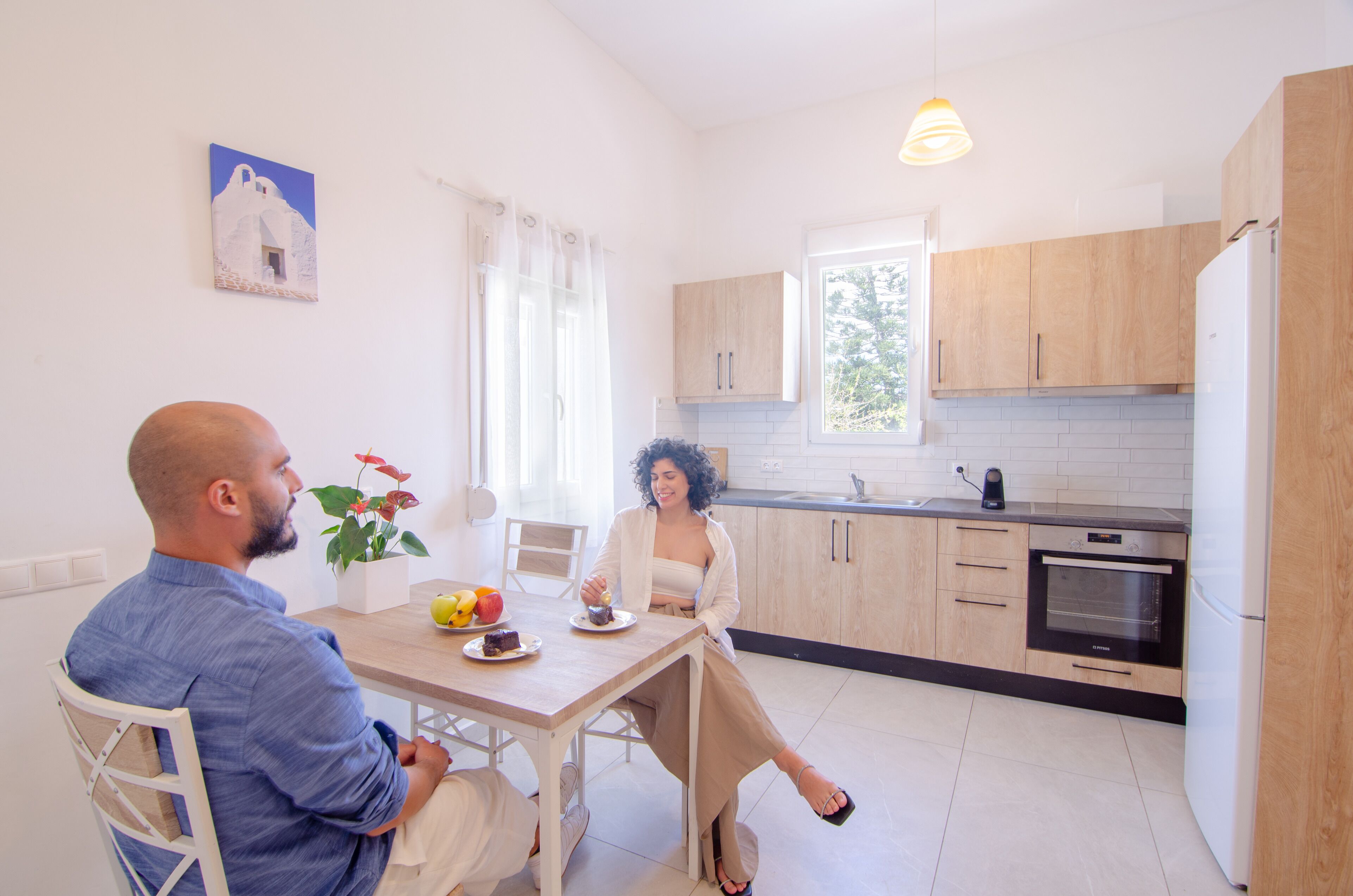 Une cuisine moderne avec des meubles en bois, un four encastré et un coin repas comprenant une table et des chaises.