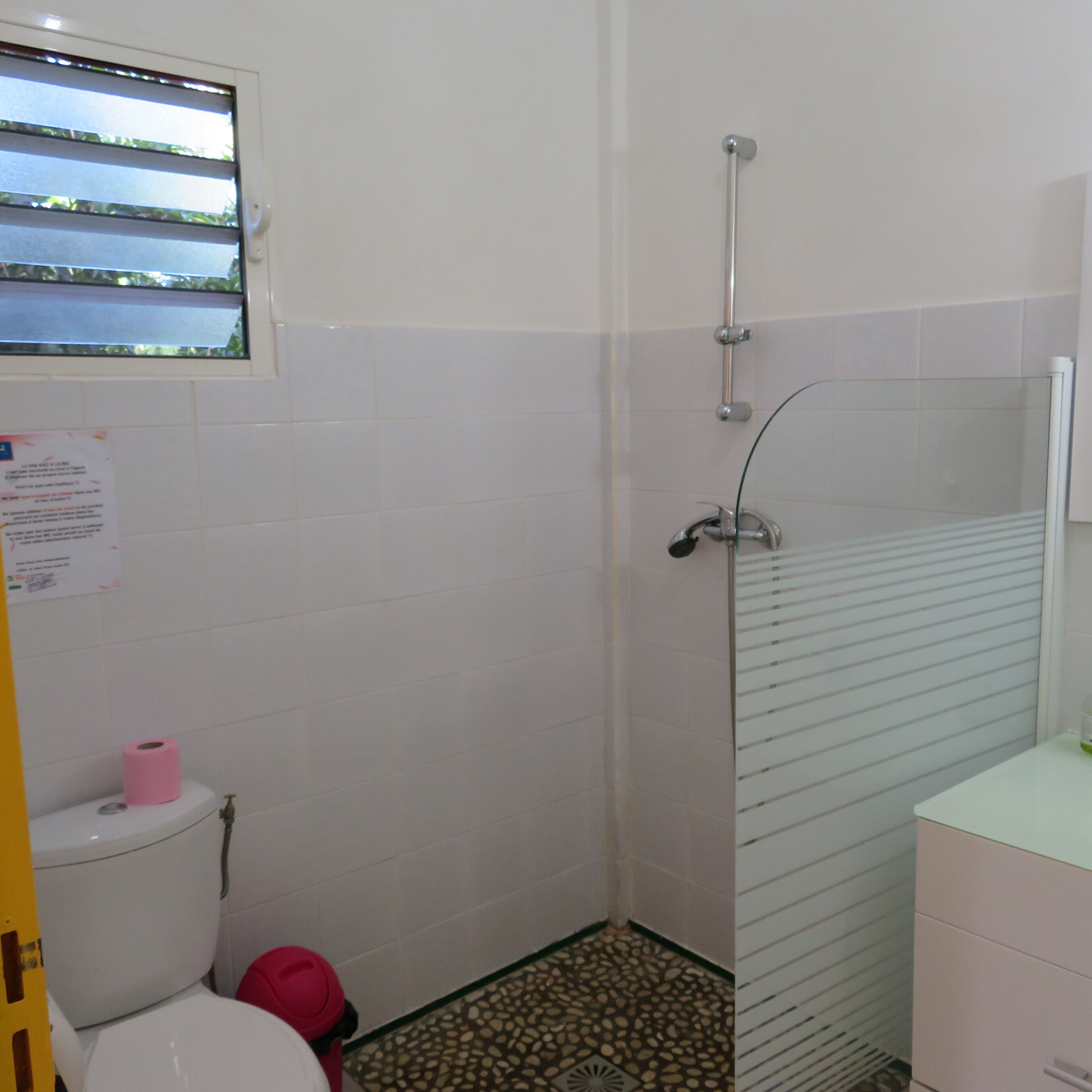 Ein kleines Badezimmer mit Toilette, Dusche und Fenster.