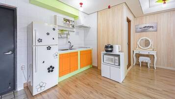 Cocina compacta con refrigerador, microondas y lavamanos.