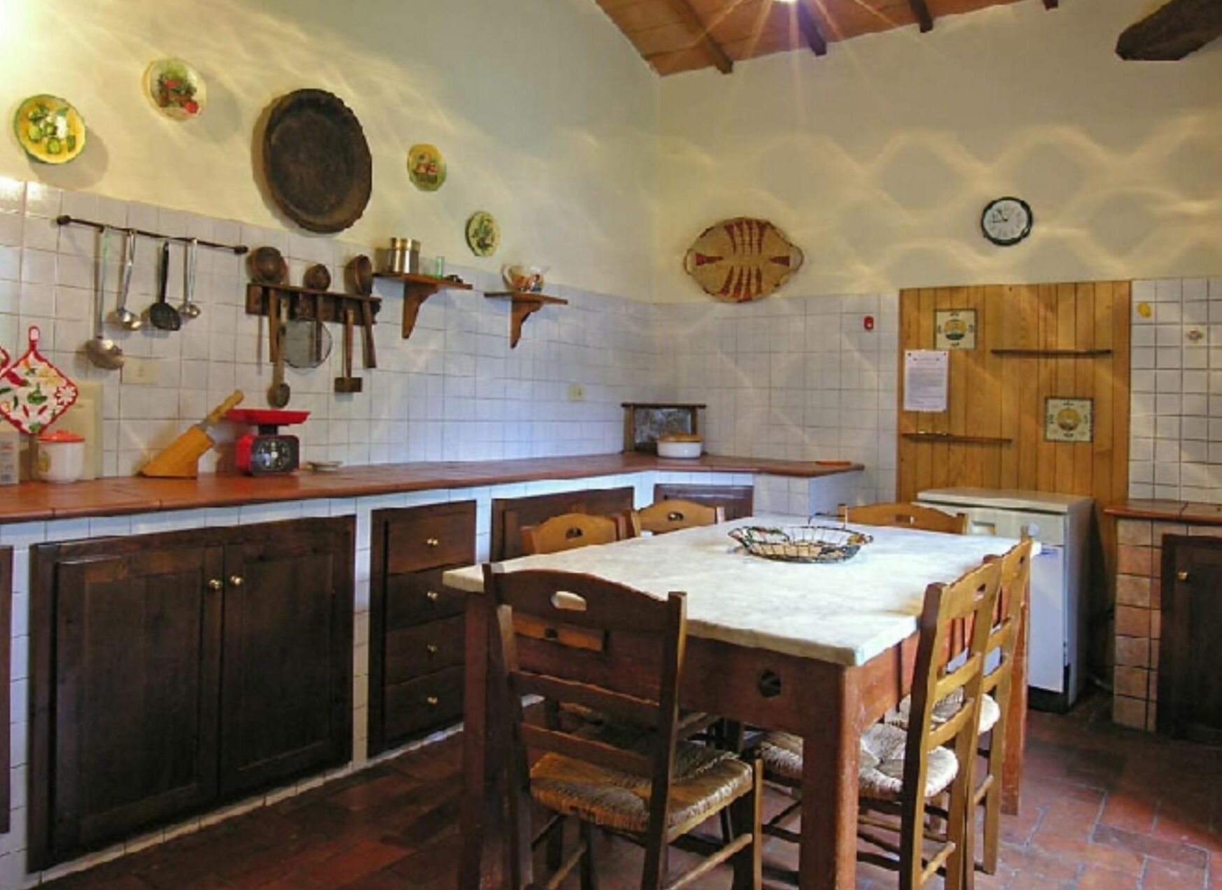 A rustic kitchen with wooden cabinets, a tiled backsplash, and a dining area with a table and chairs.