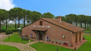 A rustic brick building labeled "Poggio del Sole" with a tiled roof, surrounded by well-maintained grass and stone pathways. - Sunflower apt With Shared Pool Family fun (Castiglione del Lago)