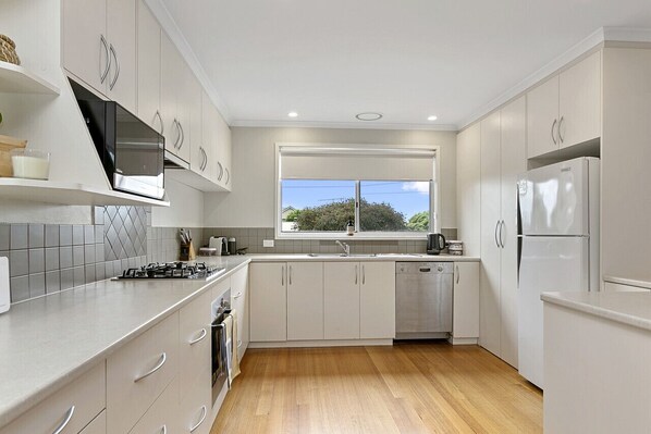 Enjoy cooking in this well-lit kitchen with a stainless steel refrigerator, oven, and dishwasher.