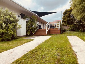 Stylish home with a flat roof, balcony, and covered porch, surrounded by a well-manicured lawn and lush greenery.