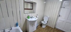 Ein Badezimmer mit Waschbecken, Spiegel, Toilette und einer Tür.